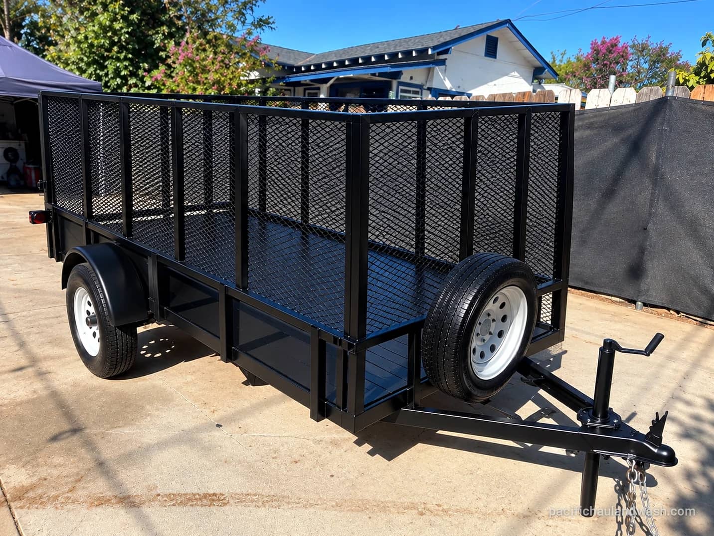 The black mesh-side utility trailer Pacific Haul & Wash uses for junk removal jobs in San Diego County