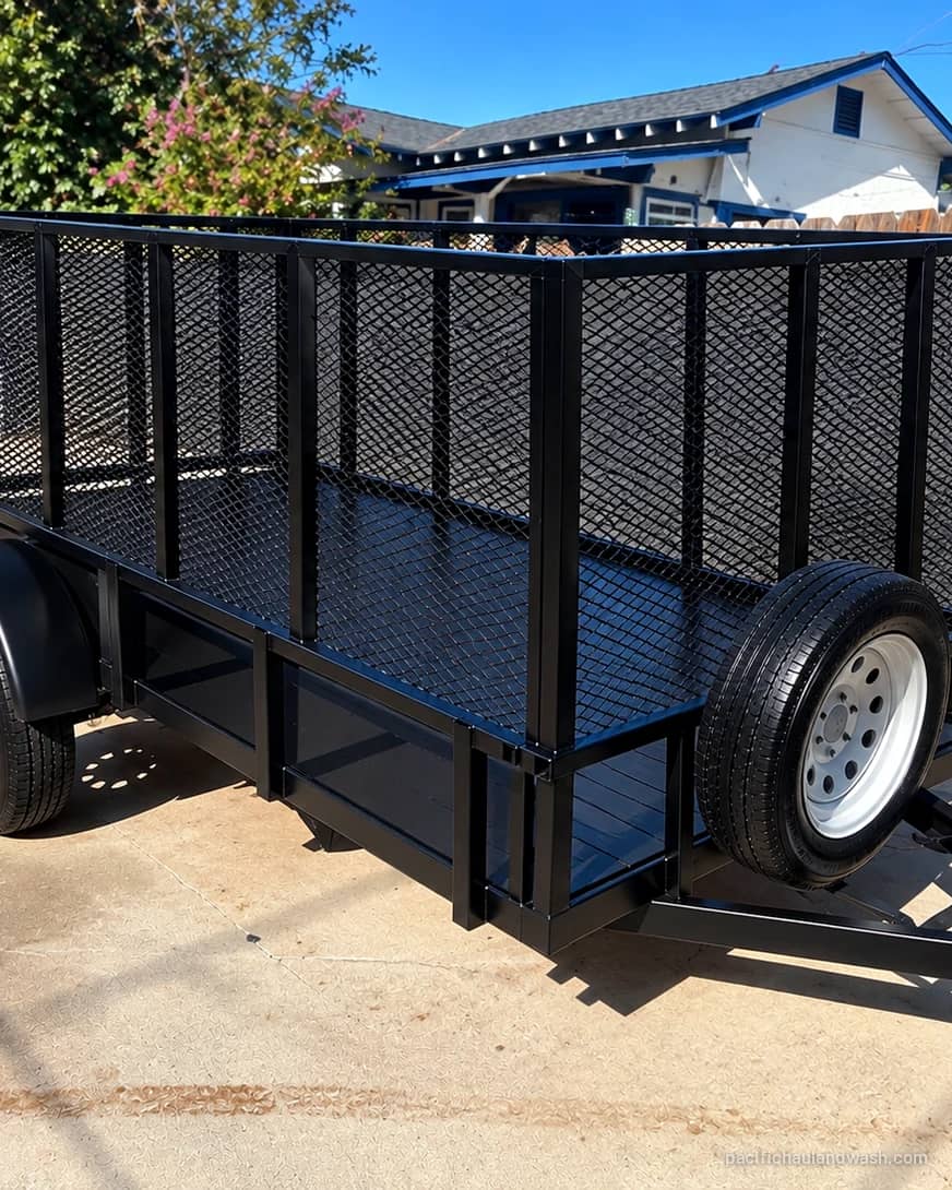 The black mesh-side utility trailer Pacific Haul & Wash uses for junk removal jobs in San Diego County