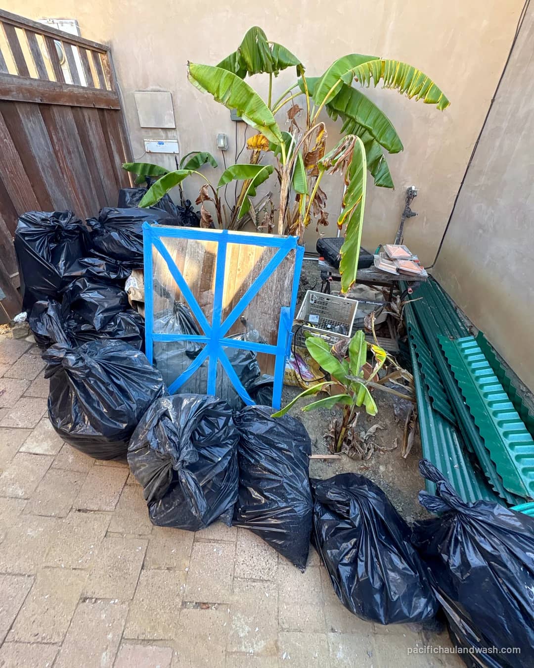 Bagged yard waste and debris stacked on a patio, ready for PHW to haul away