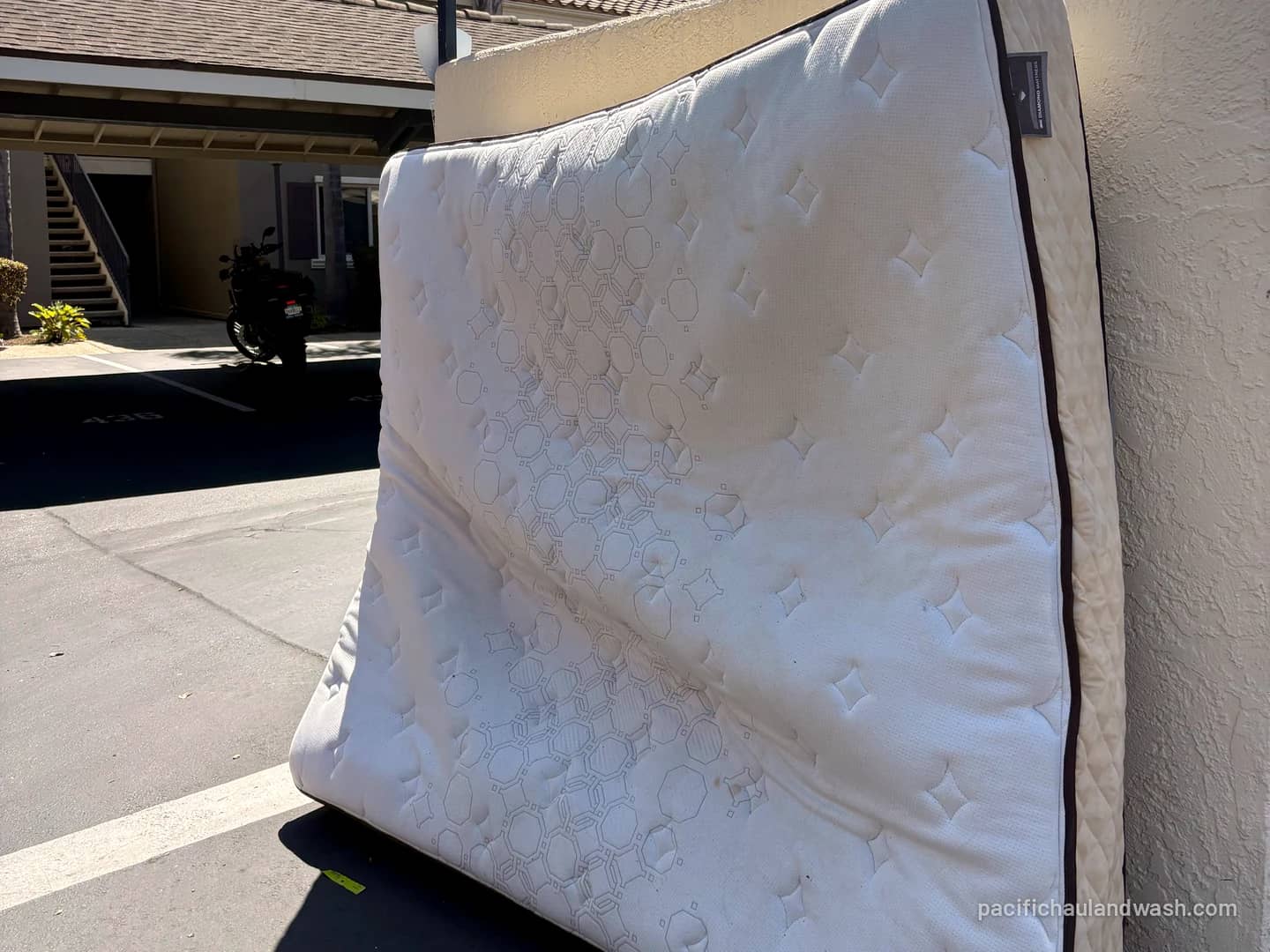 Old mattress leaning against a wall by the street, waiting for pickup in San Diego