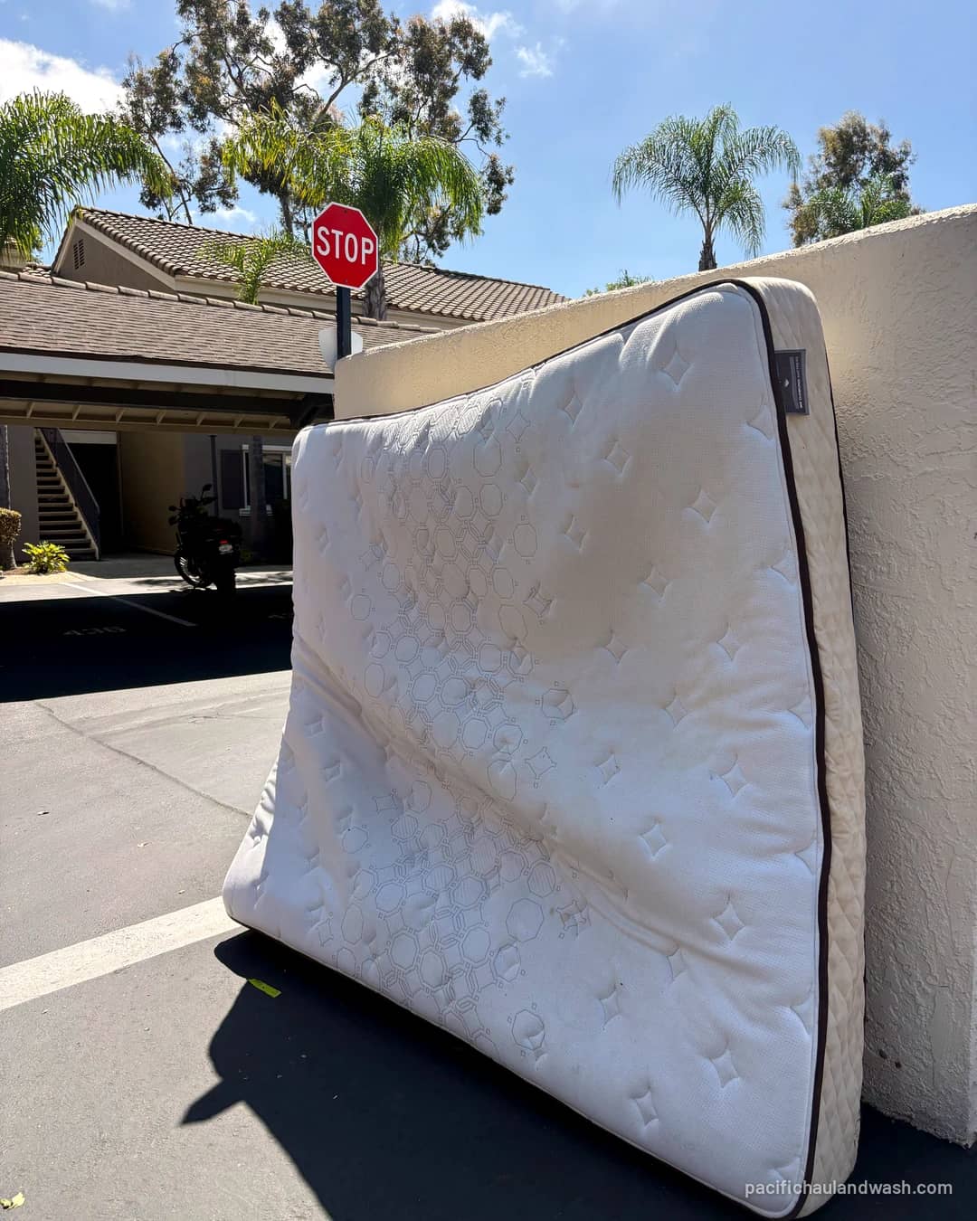 Old mattress leaning against a wall by the street, waiting for pickup in San Diego